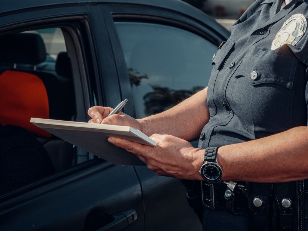 A cop giving a ticket to a driver. In New Zealand, you can soon be asked to do a roadside test by the NZ police to check for drugs like cannabis or methamphetamine.
